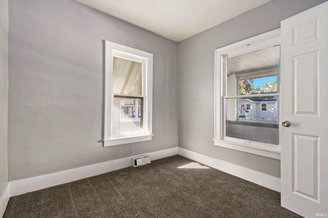 unfurnished room featuring dark colored carpet