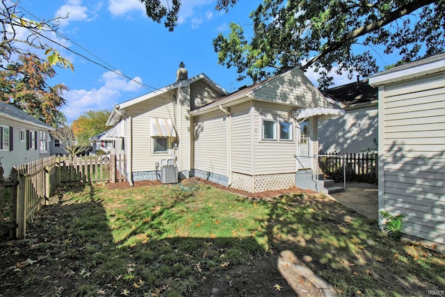 rear view of house with cooling unit and a yard