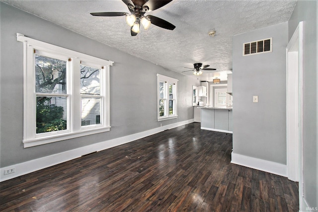 unfurnished living room with dark wood-type flooring, ceiling fan, and a textured ceiling