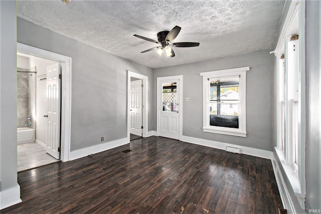 empty room with ceiling fan, dark wood-type flooring, and a textured ceiling