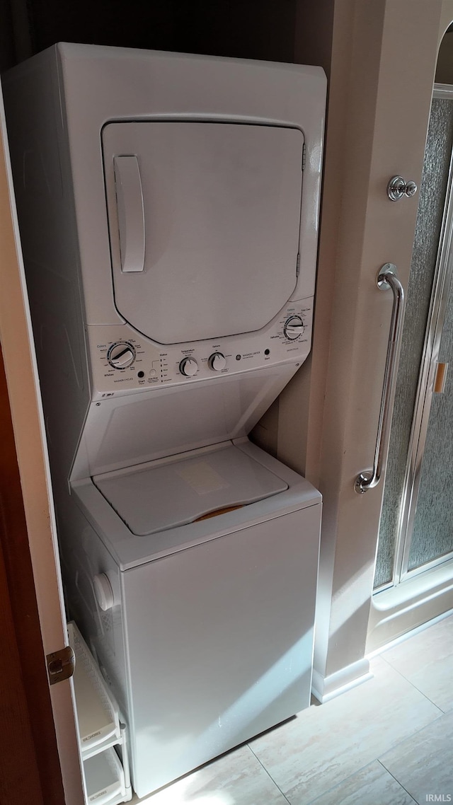 laundry area with light tile patterned flooring and stacked washing maching and dryer