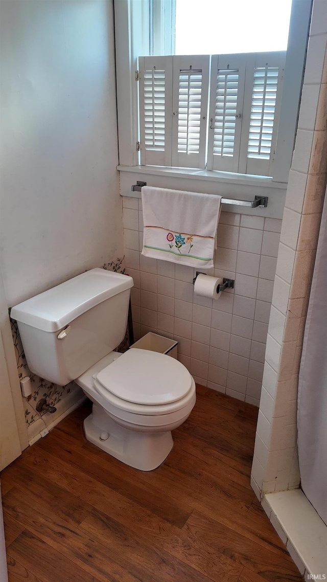 bathroom with hardwood / wood-style flooring, tile walls, toilet, and walk in shower