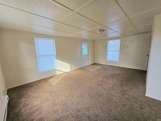 carpeted empty room featuring a baseboard radiator and a paneled ceiling