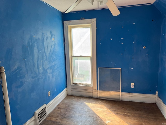 spare room with ceiling fan, vaulted ceiling, and wood-type flooring