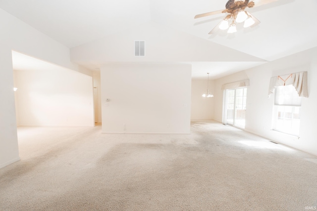 carpeted spare room featuring ceiling fan with notable chandelier and vaulted ceiling