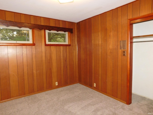 empty room with light colored carpet and wooden walls