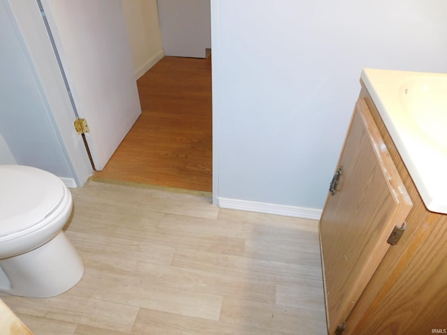 bathroom with wood-type flooring, vanity, and toilet