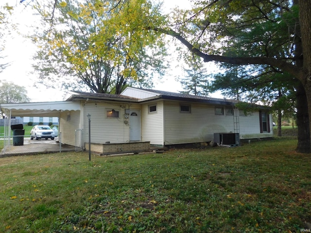 back of property featuring a yard, cooling unit, and a carport