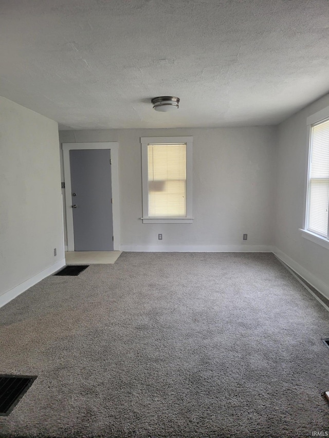 empty room featuring a textured ceiling and carpet flooring