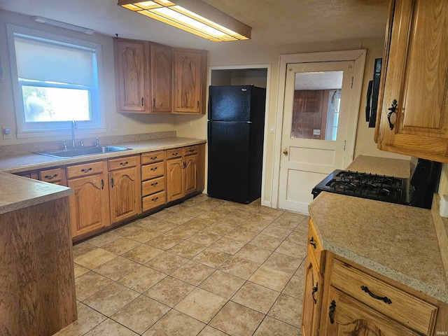 kitchen with light tile patterned flooring, sink, and black appliances