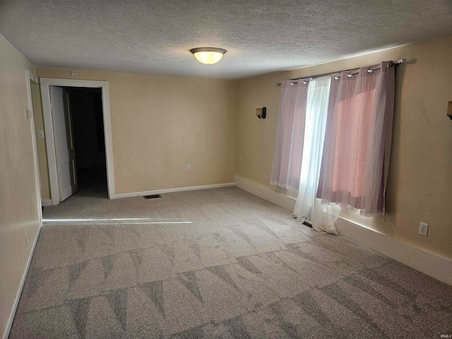 carpeted empty room with a textured ceiling