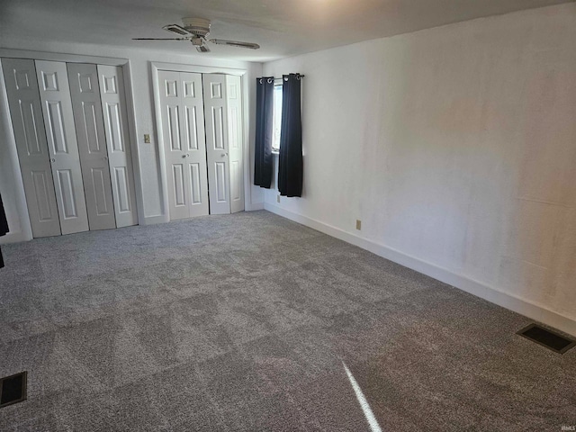 unfurnished bedroom featuring carpet floors, multiple closets, and ceiling fan