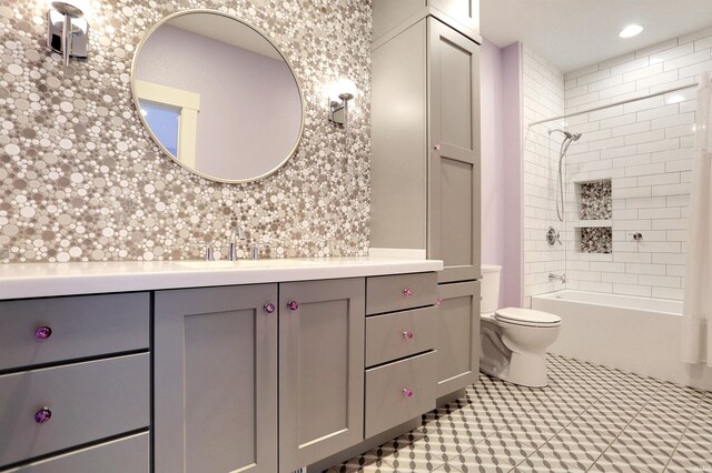 full bathroom with tiled shower / bath, vanity, and toilet