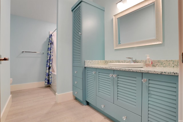 full bathroom with wood-type flooring, vanity, shower / bath combo with shower curtain, and toilet