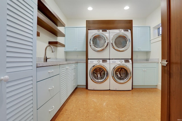 laundry area with stacked washer and clothes dryer, cabinets, and sink