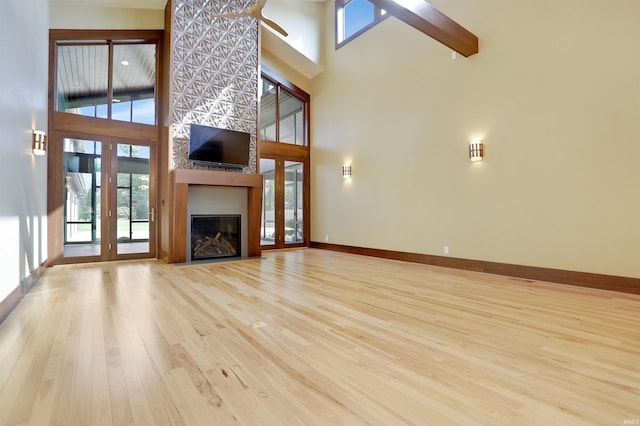 unfurnished living room featuring light hardwood / wood-style floors and a high ceiling