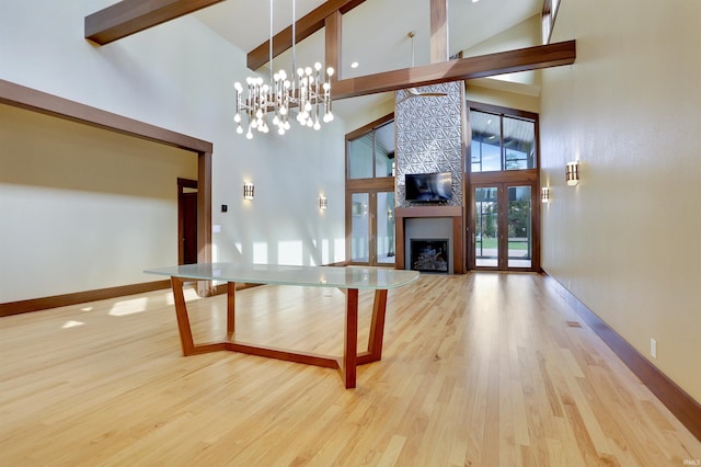 living room featuring light hardwood / wood-style flooring, a chandelier, beam ceiling, and high vaulted ceiling