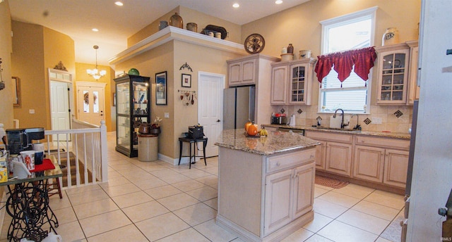 kitchen with backsplash, a kitchen island, light brown cabinetry, light tile patterned flooring, and sink