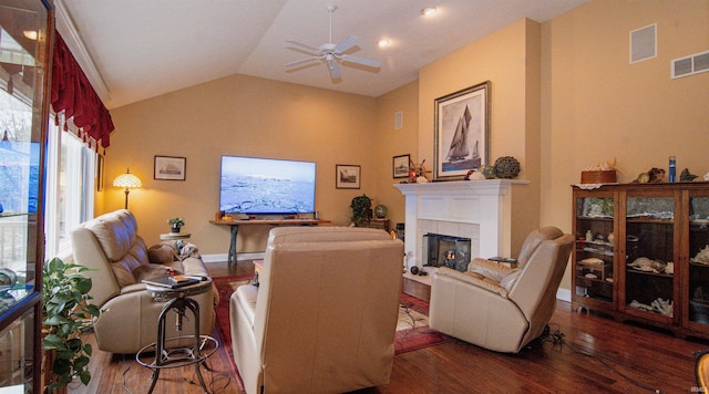 living room with lofted ceiling, dark wood-type flooring, a tile fireplace, and ceiling fan