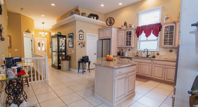 kitchen featuring tasteful backsplash, light brown cabinetry, light tile patterned flooring, a kitchen island, and stainless steel appliances