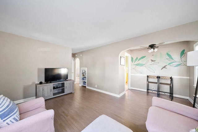 living room with ceiling fan and dark wood-type flooring