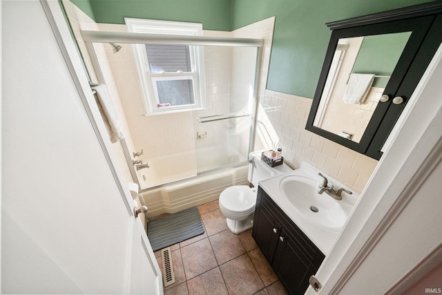 full bathroom featuring enclosed tub / shower combo, vanity, toilet, tile walls, and tile patterned flooring