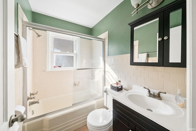 full bathroom featuring enclosed tub / shower combo, vanity, tile walls, and toilet