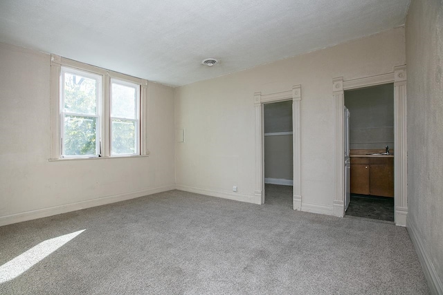 unfurnished bedroom featuring sink, a textured ceiling, and light carpet