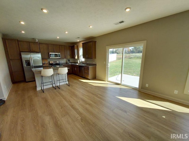 kitchen with light hardwood / wood-style floors, a kitchen breakfast bar, sink, appliances with stainless steel finishes, and a center island