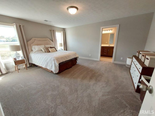 carpeted bedroom featuring a textured ceiling and ensuite bath