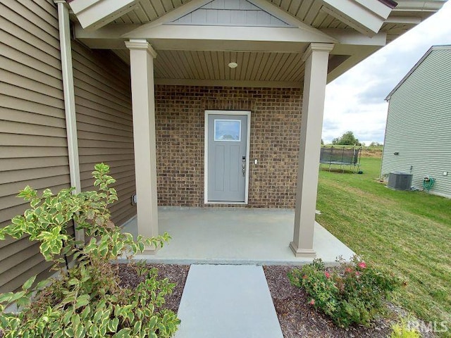 property entrance featuring cooling unit and a lawn