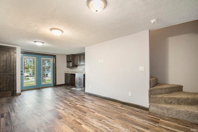 unfurnished living room with a textured ceiling and dark hardwood / wood-style flooring