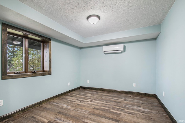 spare room featuring an AC wall unit, a textured ceiling, and dark hardwood / wood-style floors