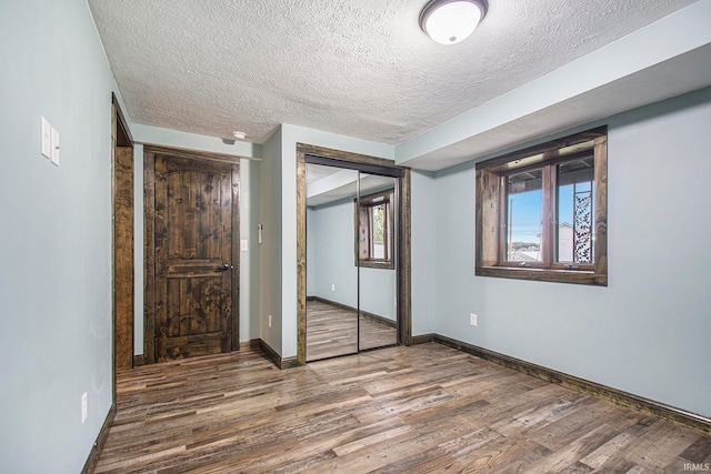 unfurnished bedroom with dark wood-type flooring, multiple windows, and a closet