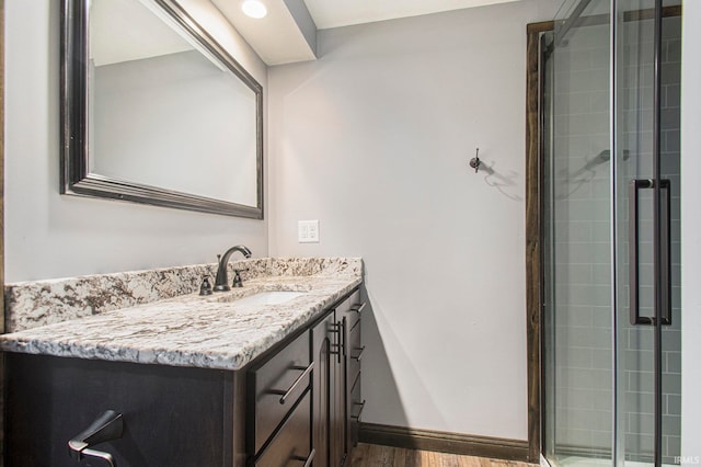 bathroom with vanity, a shower with shower door, and hardwood / wood-style flooring