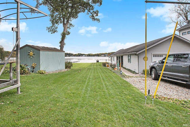 view of yard with a water view, a storage unit, and a garage