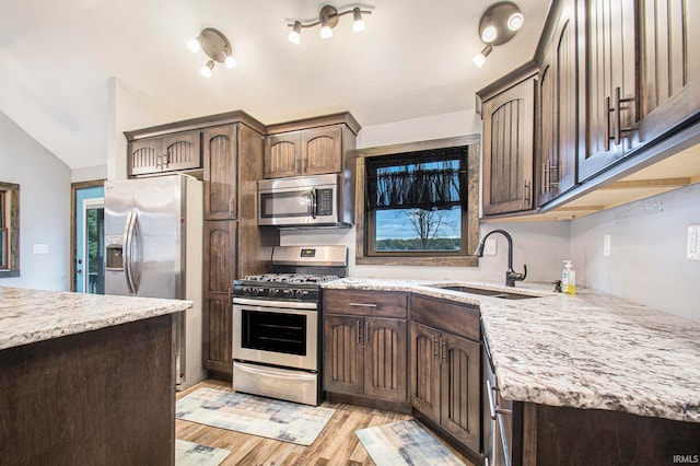 kitchen featuring lofted ceiling, dark brown cabinets, sink, light wood-type flooring, and appliances with stainless steel finishes