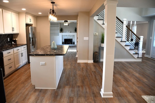 kitchen featuring dark stone countertops, a center island, decorative light fixtures, white cabinetry, and dark hardwood / wood-style flooring