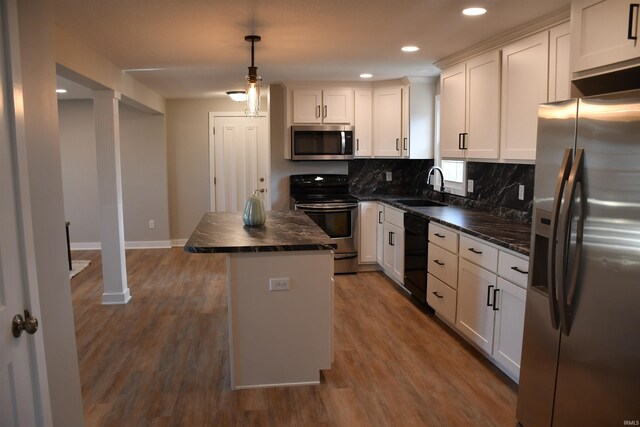 kitchen with stainless steel appliances, sink, a center island, pendant lighting, and white cabinets