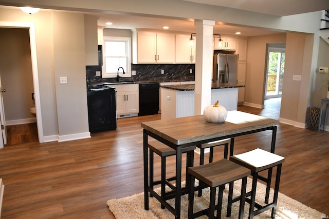 kitchen with black appliances, sink, dark hardwood / wood-style flooring, white cabinetry, and decorative backsplash