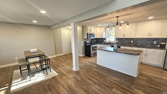 kitchen with white cabinets, a kitchen island, dark hardwood / wood-style floors, decorative light fixtures, and stainless steel appliances