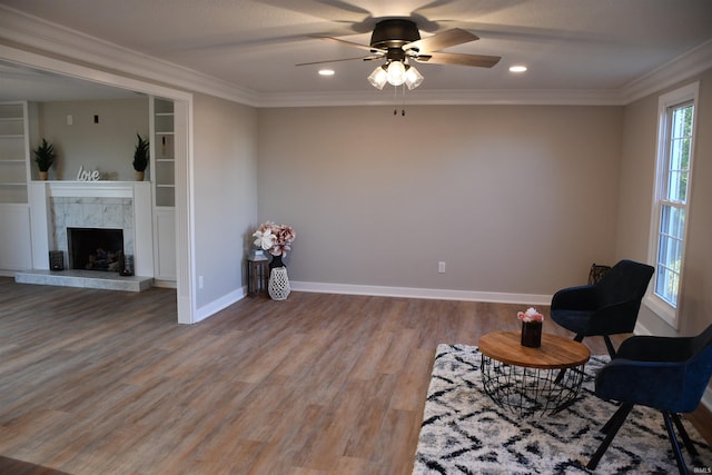 unfurnished room featuring a tiled fireplace, ceiling fan, hardwood / wood-style flooring, and ornamental molding