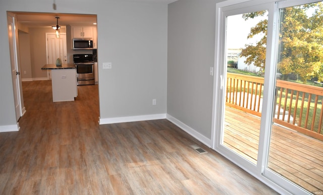 kitchen with white cabinetry, stainless steel appliances, light hardwood / wood-style flooring, and hanging light fixtures