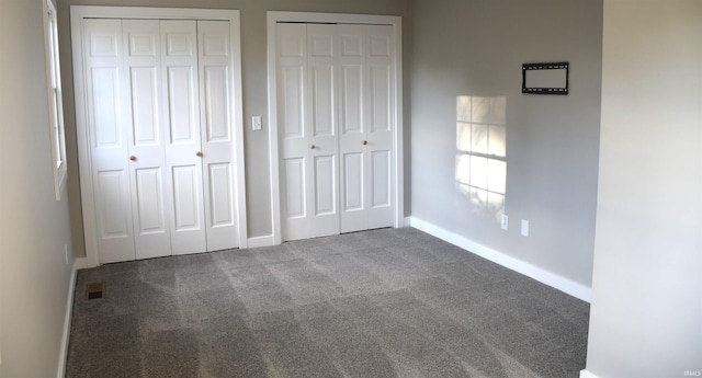 unfurnished bedroom with carpet and two closets