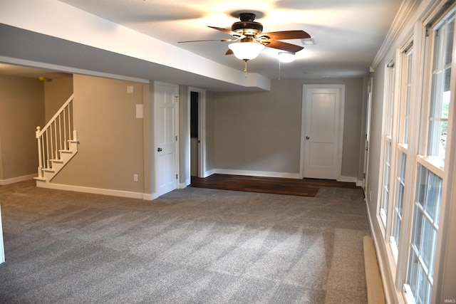carpeted empty room featuring baseboards, a ceiling fan, and stairs