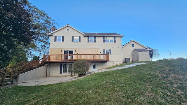 rear view of house featuring a yard, a patio area, a storage shed, and a wooden deck