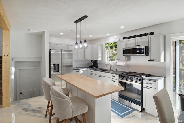 kitchen featuring a kitchen island, a breakfast bar area, stainless steel appliances, pendant lighting, and white cabinets