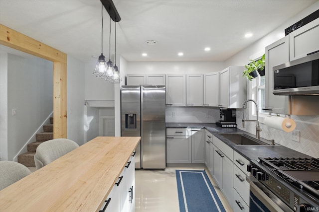 kitchen with tasteful backsplash, appliances with stainless steel finishes, sink, wood counters, and gray cabinets