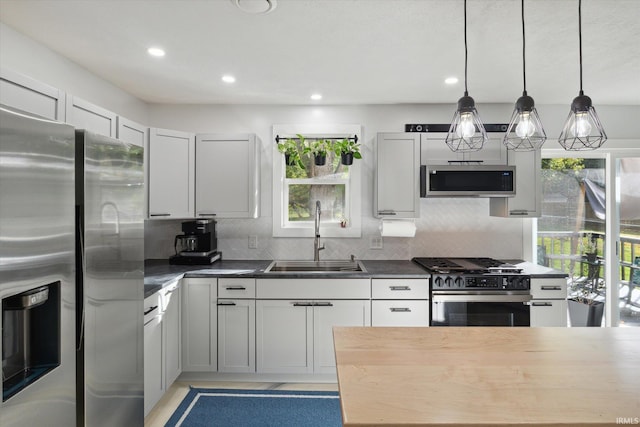 kitchen with stainless steel appliances, sink, plenty of natural light, and decorative light fixtures