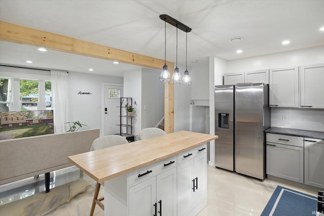 kitchen with tasteful backsplash, butcher block countertops, hanging light fixtures, stainless steel fridge, and a breakfast bar area